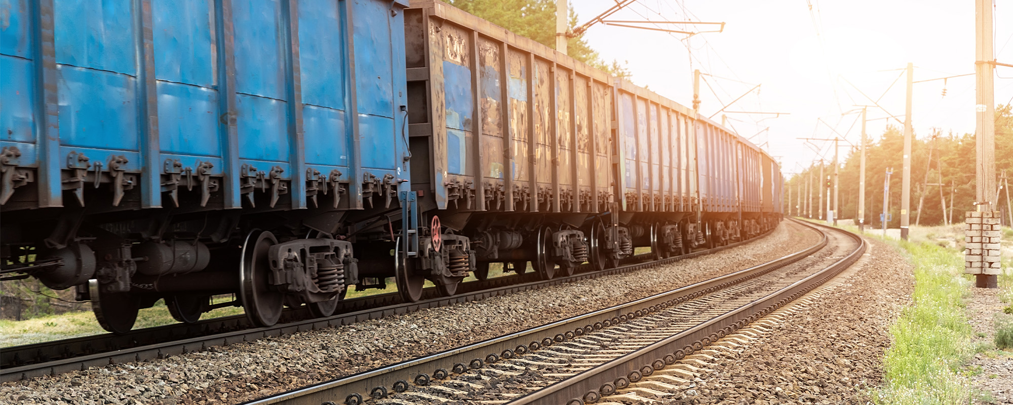 Heavy cargo freight rusty train wagons moving on railway on sunset or sunrise day time Industrial materials transportation and goods delivery concept Old rusty wagons moving by rail