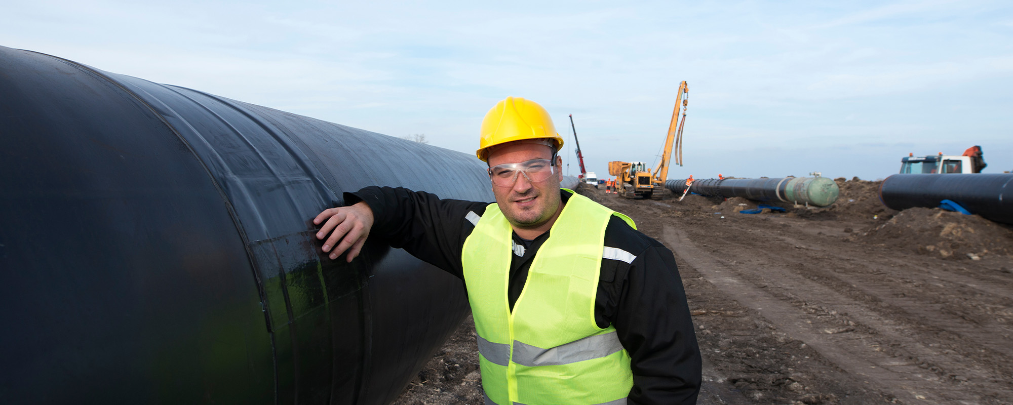 Portrait of an oilfield worker standing by gas pipe at construction site