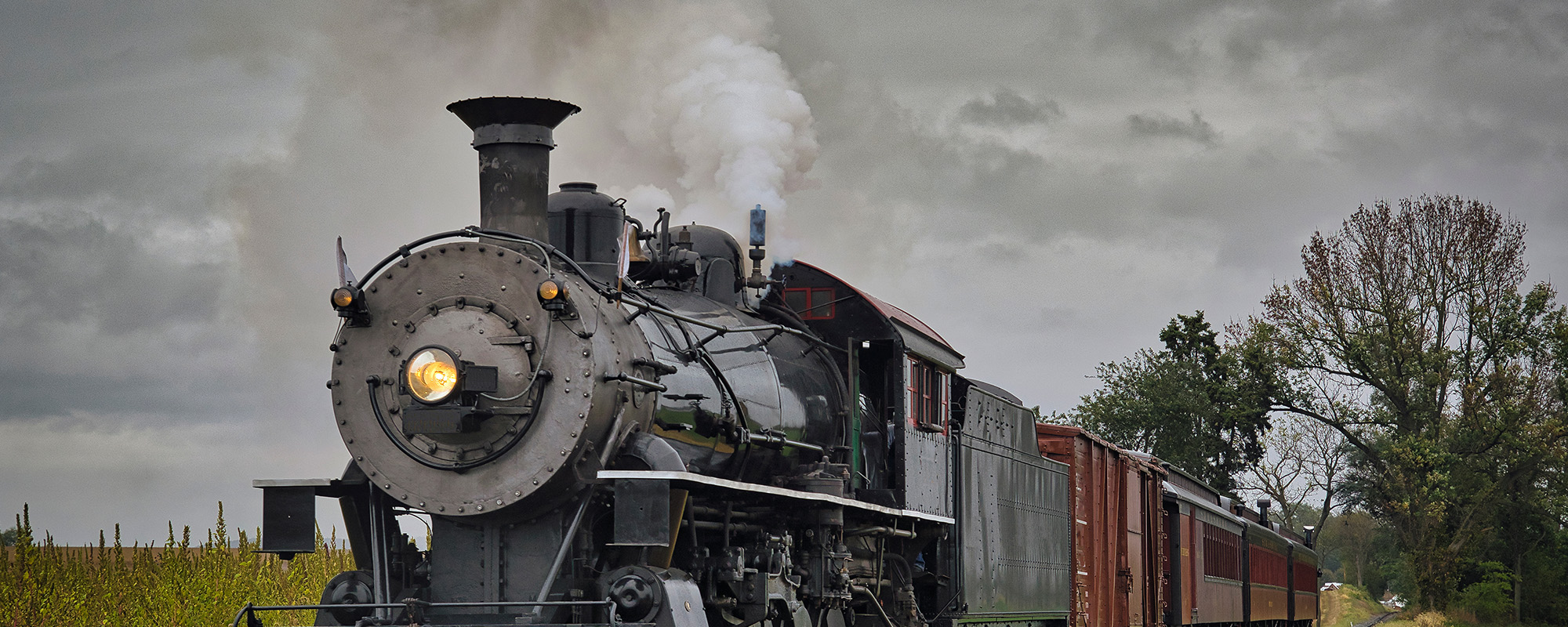 an antique restored steam freight train approaching head on blowing smoke and steam
