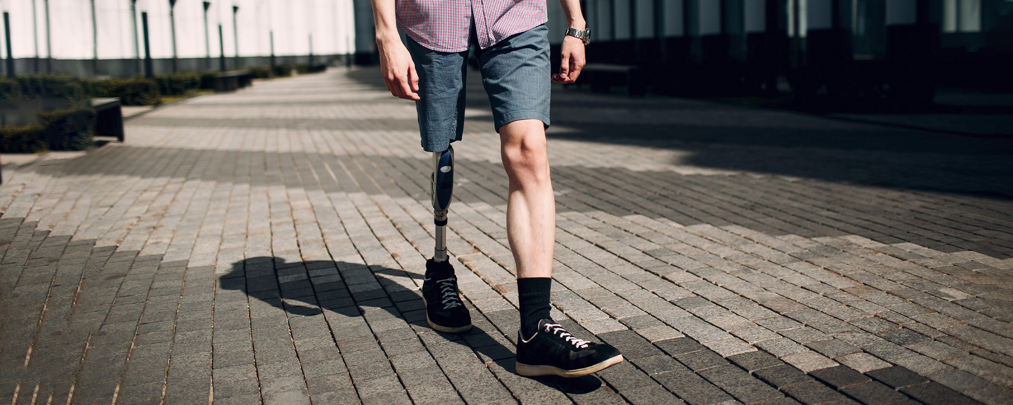 disabled young man with foot prosthesis walks along the street.
