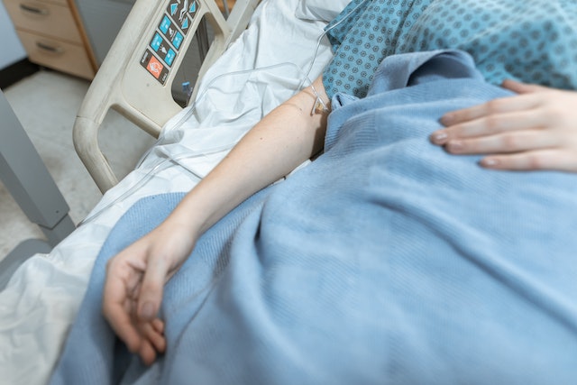 person in hospital bed with iv tubes